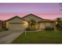 Charming single-story home featuring a well-manicured lawn, lush landscaping, and an attached two-car garage at 2710 93Rd E Ct, Palmetto, FL 34221