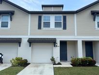 Two-story townhome with beige siding, a white garage door, and a blue front door at 5812 Ocean Isle Dr, Nokomis, FL 34275