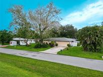 Charming single-story home with a well-manicured lawn, mature trees, and a long driveway leading to the garage at 1208 Francis Ave, Sarasota, FL 34232
