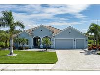 Charming single-story home featuring a lush lawn, mature palms, a paver driveway, and a three-car garage at 15808 42Nd E Gln, Parrish, FL 34219