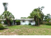 Cozy single-story home featuring a white exterior and a lush lawn with mature palm trees at 2711 Kilgore Pl, Sarasota, FL 34235