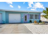Charming home with a light blue exterior, white garage door, and vibrant purple door and shutter accents at 441 62Nd St, Holmes Beach, FL 34217