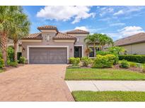 Beautiful single-story home featuring a paver driveway, two-car garage, tile roof and lush tropical landscaping at 5596 Cantucci St, Nokomis, FL 34275