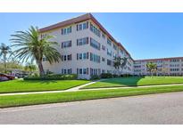 Beautiful exterior of a residential building with lush green grass and mature landscaping under a clear blue sky at 9950 62Nd N Ter # 401, St Petersburg, FL 33708