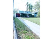 Charming home with a long driveway, lawn, and mature trees at 126 W North St, Tampa, FL 33604