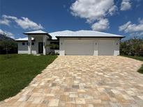 Beautiful single-Gathering home featuring a three-car garage and elegant stone paver driveway at 13654 Allamanda Cir, Port Charlotte, FL 33981