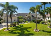 Charming single-story home featuring a well-manicured lawn, lush landscaping, and beautiful palm trees at 2505 Rio Tiber Dr, Punta Gorda, FL 33950