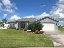 One-story home with gray exterior, attached garage, and landscaped lawn at 1307 Tidy Ln, Punta Gorda, FL 33983