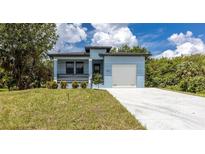 Modern single-story home with light blue exterior, attached garage, and landscaped lawn at 3225 Amanda St, Punta Gorda, FL 33950