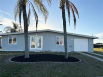 Charming single-story home with a fresh exterior, palm trees and a well-manicured lawn at 4127 Gardner Dr, Port Charlotte, FL 33952