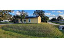 Cute yellow house with solar panels and a well-maintained lawn at 21427 Michigan Ave, Port Charlotte, FL 33952