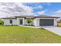 Charming single-story home with a well-manicured lawn and a modern two-car garage at 23359 Mcmanaway Ave, Port Charlotte, FL 33980