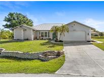 Single-story home with metal roof, landscaped yard, and attached garage at 18882 Ayrshire Cir, Port Charlotte, FL 33948