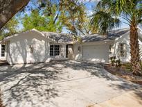 White house exterior with a two-car garage, mature trees, and a landscaped yard at 1291 Beacon Dr, Port Charlotte, FL 33952