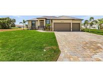 Single-story home with two-car garage, paver driveway, and lush lawn at 24237 San Lucas Ln, Punta Gorda, FL 33955