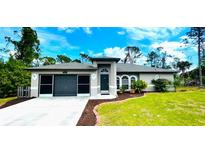 Single-story home with a two-car garage and well-maintained landscaping at 66 Wylam Dr, Port Charlotte, FL 33954