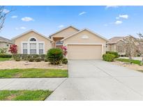 Tan house with a two-car garage and nicely landscaped yard at 24477 Lakeside Mnr, Punta Gorda, FL 33980