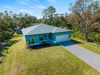 New teal home with a white garage door and paver driveway at 1417 Longson St, Port Charlotte, FL 33953