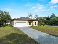 Charming single-story home with a paved driveway, attached two-car garage, and manicured lawn under a bright blue sky at 3376 Dunbar St, Port Charlotte, FL 33948