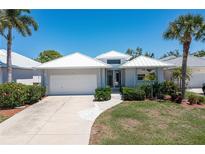 Single-story home with white exterior, attached garage and lush landscaping at 15 Windward Pl, Placida, FL 33946