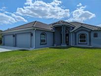 Two-story house with a gray exterior, three-car garage, and landscaping at 2761 Newman Dr, North Port, FL 34288