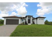 Beautiful, modern single-Gathering home with a lush green lawn, paved driveway, and a two-car garage at 8124 Welsford Rd, Port Charlotte, FL 33981
