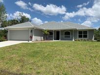 Charming single-story home with a well-manicured lawn, attached garage, and inviting front porch at 17184 Wintergarden Ave, Port Charlotte, FL 33948