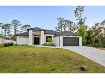 Beautiful one-story home with a modern design, manicured lawn, and a two-car garage on a sunny day at 5815 Casanova Ave, North Port, FL 34291