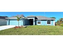 One-story light blue house with attached garage and palm trees at 9267 Waldrep St, Port Charlotte, FL 33981