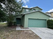 Two-story house with a green exterior, two-car garage, and landscaping at 9454 Wellstone Dr, Land O Lakes, FL 34638