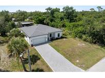 New construction home featuring a paver driveway, attached garage and tropical landscaping at 2049 Delta St, Port Charlotte, FL 33952
