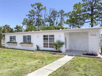 Charming Ranch style home with white brick facade and well-manicured lawn at 22239 Midway Blvd, Port Charlotte, FL 33952