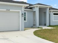 Inviting single-Gathering home featuring a bright, light-blue exterior with a white two-car garage and walkway at 13348 Rayburn Ln, Port Charlotte, FL 33981
