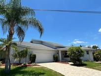 Single-story home with a white exterior, tiled roof and palm trees at 65 Ocean Dr, Punta Gorda, FL 33950