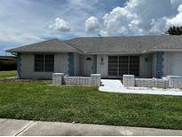 Brick ranch home with gray roof, landscaping, and walkway at 4419 Crews Ct, Port Charlotte, FL 33952