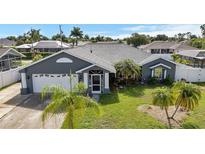 Gray house with white garage door, landscaped lawn, and palm trees at 126 Allworthy St, Port Charlotte, FL 33954