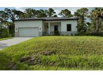 Single-story home with attached garage and grassy lawn at 13460 Tolman Ave, Port Charlotte, FL 33953