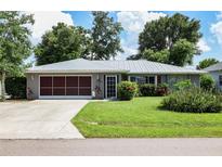 Charming home featuring a metal roof, well-manicured lawn, and beautiful flowering shrubbery at 23117 Hillsdale Ave, Port Charlotte, FL 33954