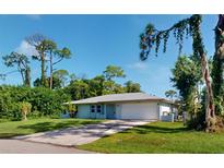 Light blue single story house with a two-car garage and spacious yard at 20340 Zelda Ave, Port Charlotte, FL 33952