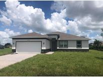 One-story home with a white and gray exterior, two-car garage, and a well-maintained lawn at 16216 Minorca Dr, Punta Gorda, FL 33955