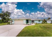 Front view of a charming light blue single-story house with a neatly landscaped lawn at 7456 Jennifer Dr, Port Charlotte, FL 33981