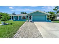 Charming teal house with a well-maintained lawn and driveway at 21239 Argyle Ave, Port Charlotte, FL 33954