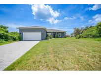 Charming single-story home with a gray exterior, white garage door, and landscaped yard at 725 Essex Ave, Port Charlotte, FL 33948