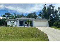 One-story light blue house with white garage and landscaping at 18265 Koala Ave, Port Charlotte, FL 33948