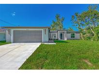 Newly built home with a gray garage door and a well-manicured lawn at 4582 Enid Ln, North Port, FL 34288