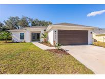 Newly constructed home with a modern exterior, two-car garage, and landscaped front yard at 1019 Cazenovia St, Port Charlotte, FL 33952