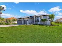 Beautiful two-story home featuring a well-manicured lawn, complemented by lush landscaping and a two-car garage at 24051 Pyramid Way, Punta Gorda, FL 33955