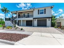 Two-story coastal home featuring a 2-car garage, covered balcony, and well-manicured landscaping at 611 W Olympia Ave, Punta Gorda, FL 33950