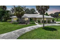 Single-story home with a tiled roof, palm trees, and a landscaped lawn at 4041 Michel Tree St, Port Charlotte, FL 33948