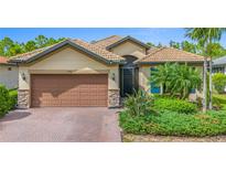 Attractive single-story home with a brown garage door and lush landscaping at 1596 Hyssop Loop, North Port, FL 34289